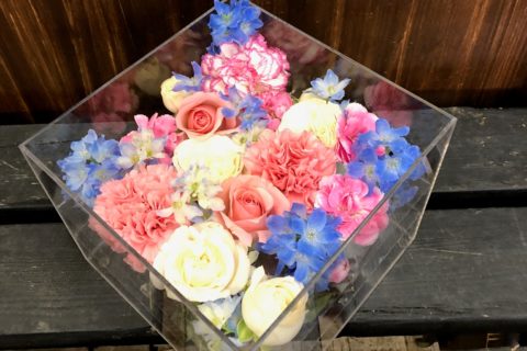 アクリルケースに納められたピンクのガーベラなどの色とりどりの花々。