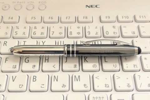 パソコンのキーボードの上に置かれているメタリック色の当社のボールペン