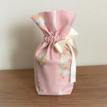 ピンク色の生地をベースに花柄のアクセントの付いたペット用のお骨袋